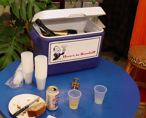 This is a photo of a cooler full of champagne with a sign that says "Here's to Randall."